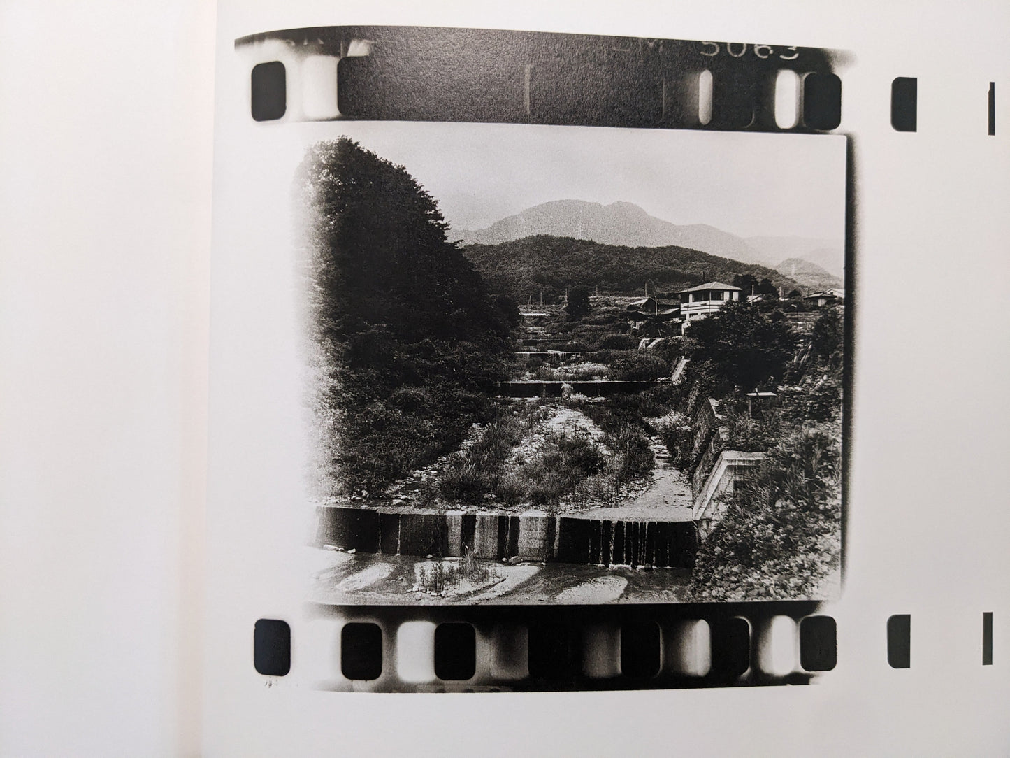 Filmstrip-style photograph of a rural Japanese village by Daido Moriyama