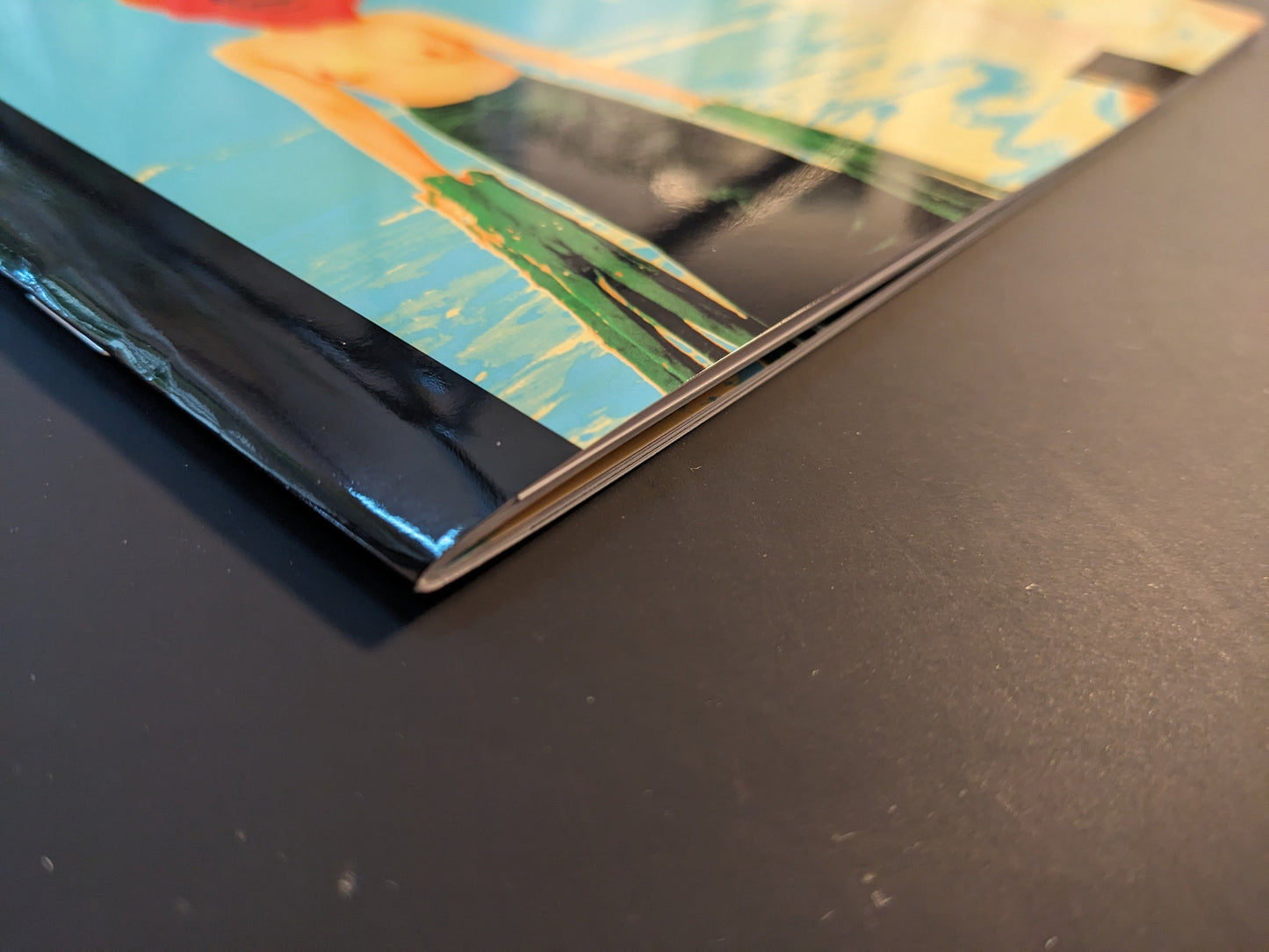 Close-up view of the softcover spine and edge of Daisuke Matsumoto’s photobook “AKARUIMIRAI” showing the glossy binding and pages.