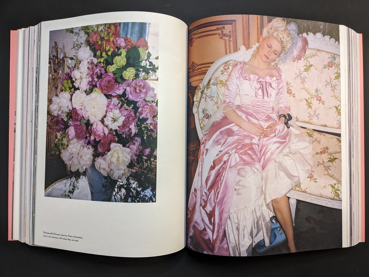 Photograph from Marie Antoinette featuring a floral arrangement and Kirsten Dunst in a pink Rococo dress resting on a sofa, from Archive by Sofia Coppola