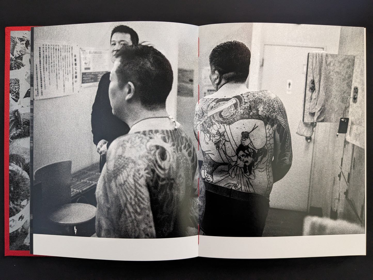 Rear view of tattooed men in a tiled Japanese bathroom.