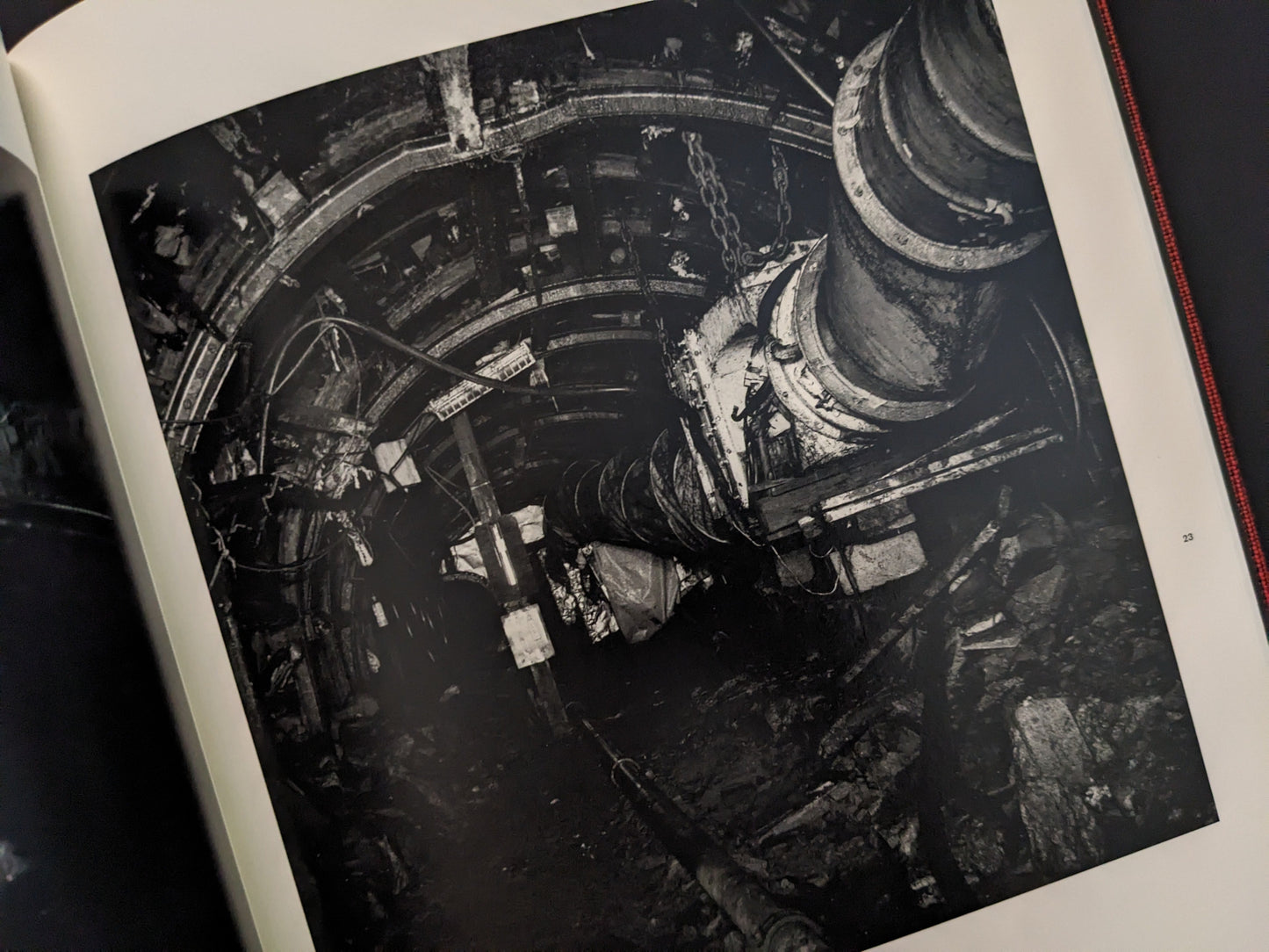 Photograph of a dark underground mining tunnel with heavy machinery, from Berg Werk by Sincei Yamamoto