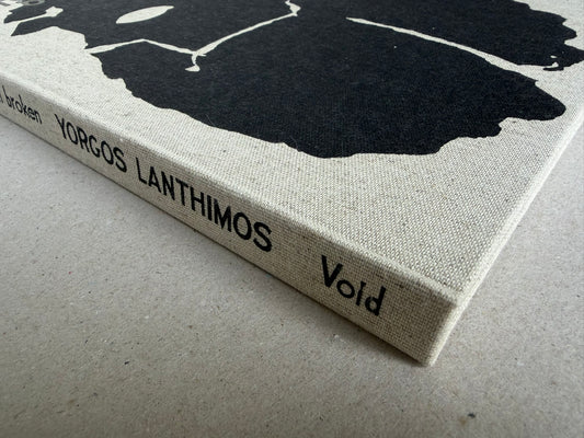Close view of the cloth spine of Dear God, the Parthenon is still broken by Yorgos Lanthimos, with the title and Void printed in black.