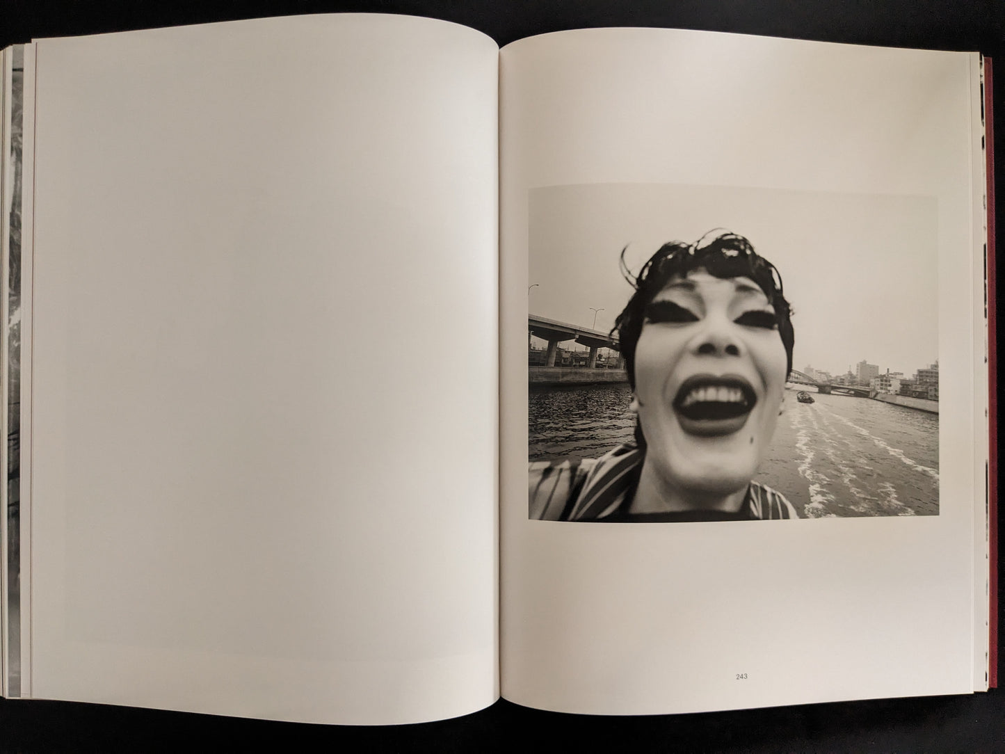 Wide-angle photograph of a performer with exaggerated makeup, smiling at the camera on a river.
