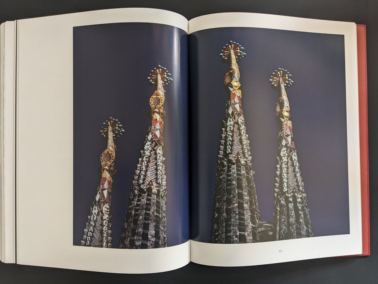 Full-color photograph of the towers of La Sagrada Familia, shot from a low angle against a deep blue sky.