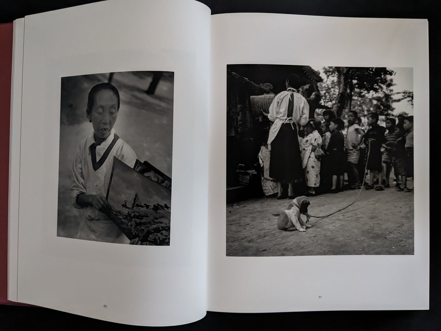 Open book showing black and white photographs of a person and a dog in a traditional setting.