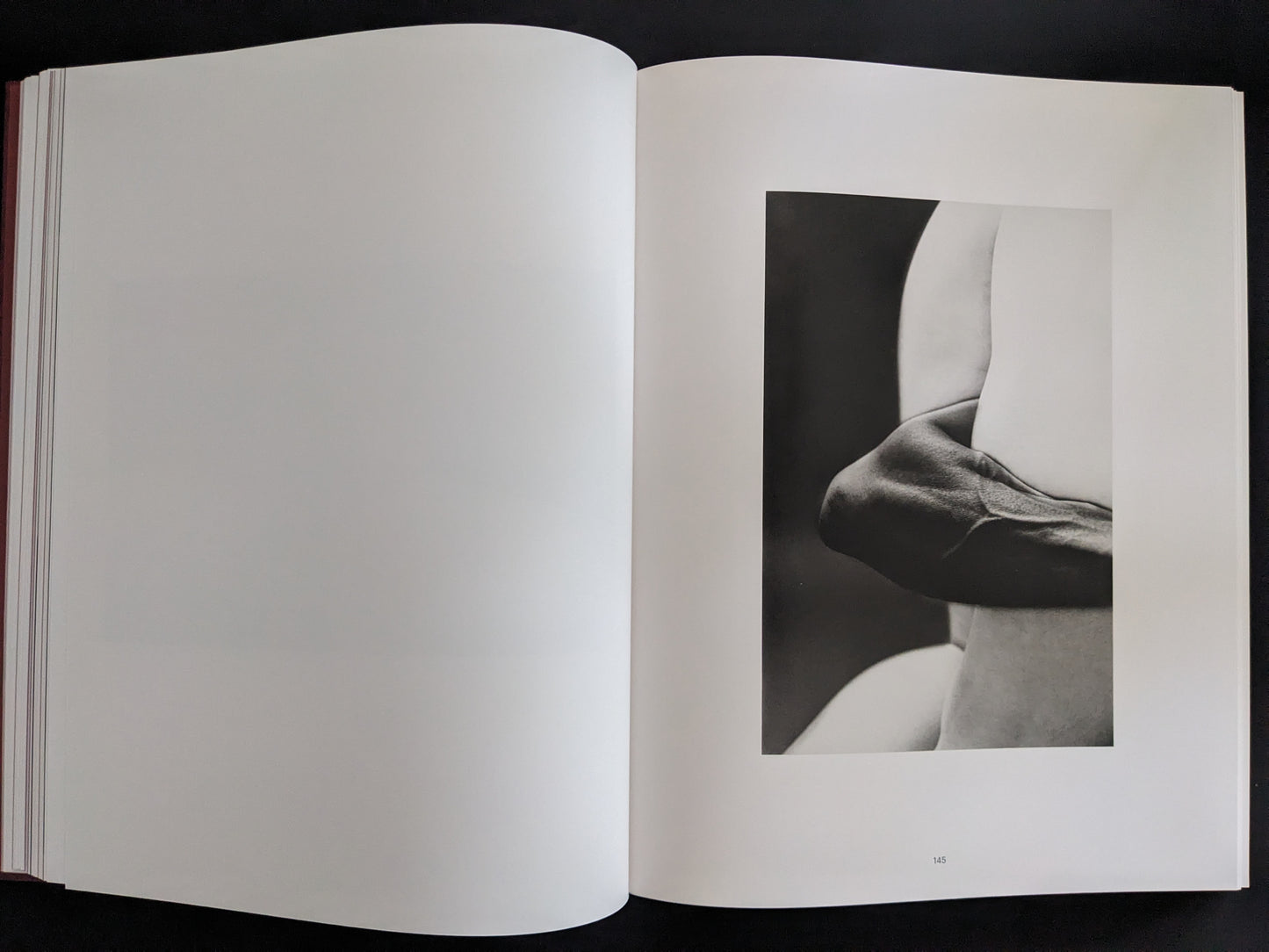 Minimalist black-and-white photograph showing a folded arm and torso composition