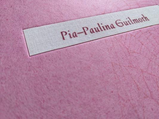 Close-up of the fabric nameplate reading Pia-Paulina Guilmoth on the pink cover.
