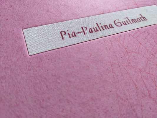 Close-up of fabric nameplate with author’s name "Pia‑Paulina Guilmoth" on the cover of the book "Flowers Drink the River"
