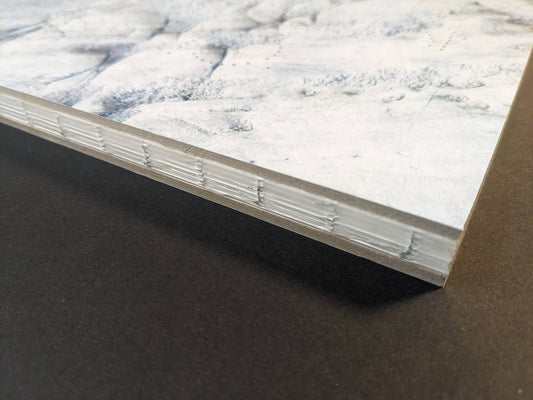 Close-up of Glass Mountain photobook, showing the book block edge and binding detail with chopped boards cover