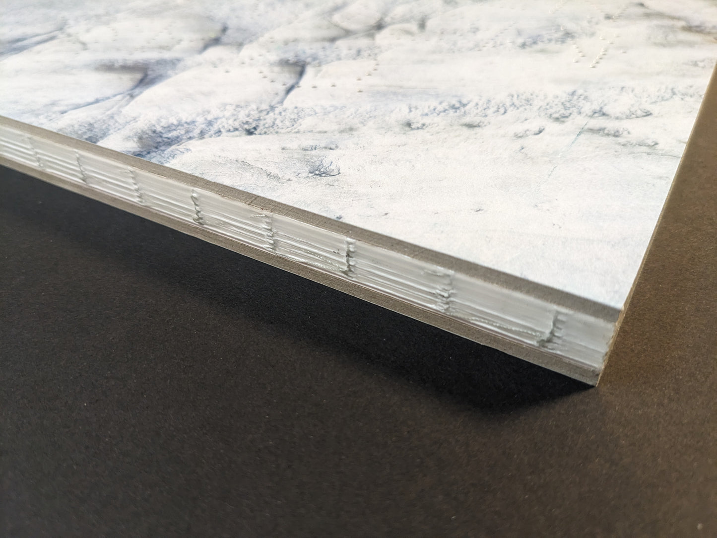 Close-up of Glass Mountain photobook showing the book block edge and binding detail with chopped boards cover