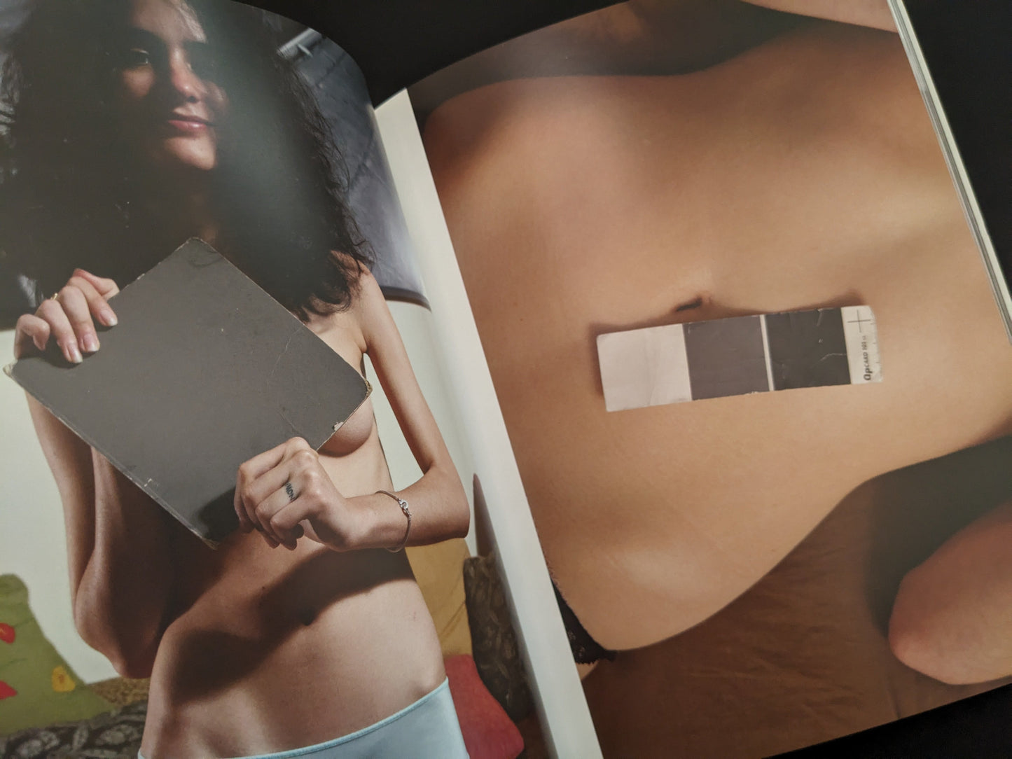 Photo of a nude woman lying down with a grey card placed on her belly from the photobook "Grey Cards" by Richard Kern.