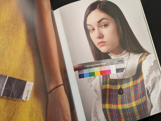 Portrait of a young woman holding a colorful Kodak chart for color calibration, from "Grey Cards" by Richard Kern.