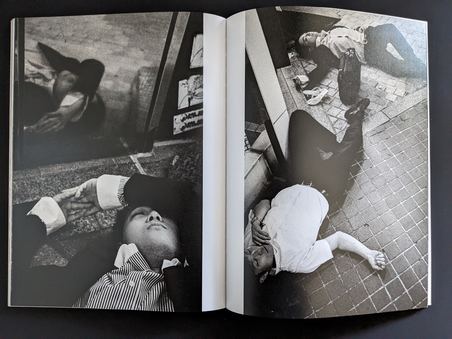 Black and white photo of businessmen lying unconscious in urban Tokyo