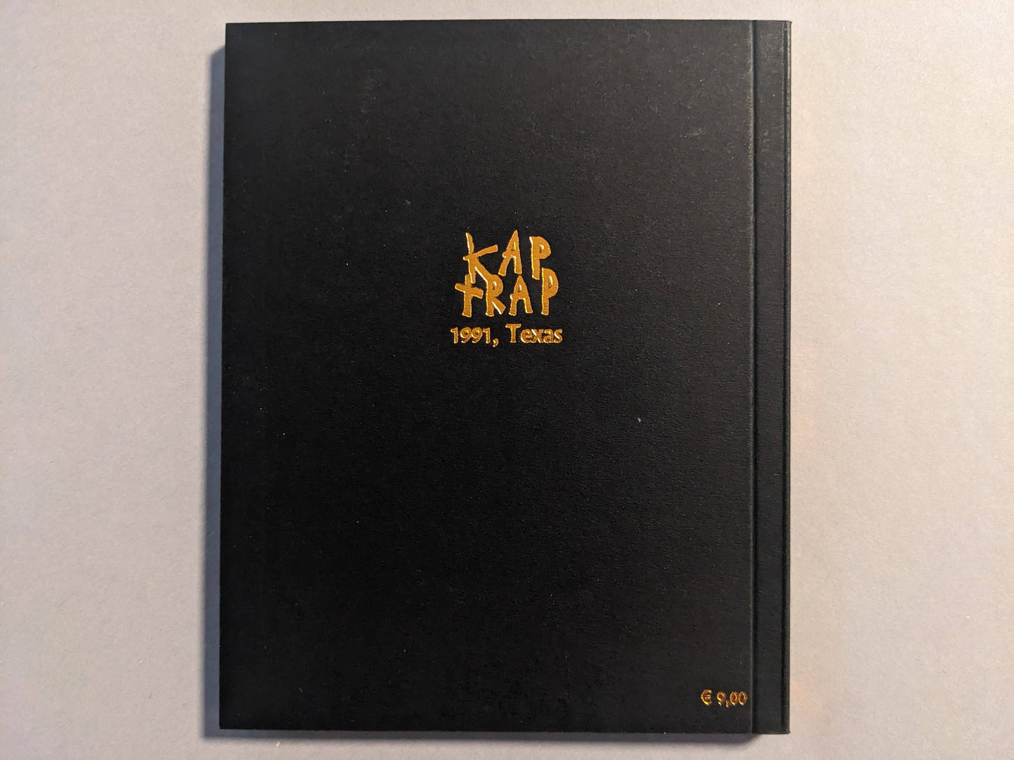 Back cover of KAP TRAP with gold foil illustration on a black background.