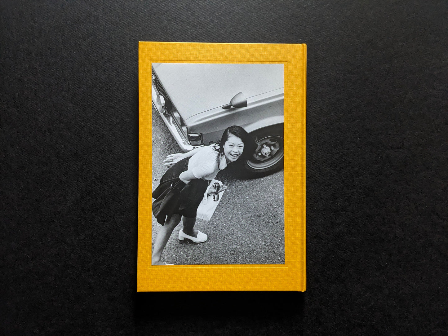 Back cover of Masahisa Fukase 1961–1991 Retrospective with an inset black-and-white photograph of a smiling woman beside a car.