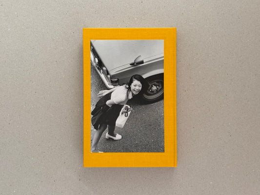 Masahisa Fukase 1961–1991 Retrospective, front cover on a grey surface, showing a black-and-white photograph framed by a yellow border.