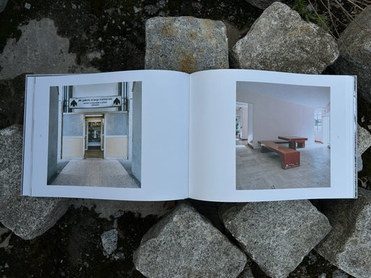 Open book 'Alveare' by Matthias Heiderich and Andrea Belfi showing two architectural interior photos on a stone background - IIKKI - Lokator100