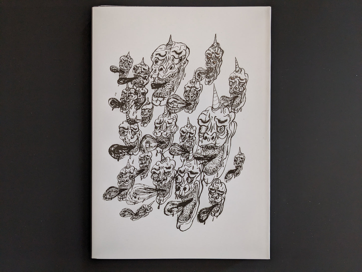 Back cover of The Life of Namazuko featuring a pattern of grotesque demon heads with horns and flowing tongues.