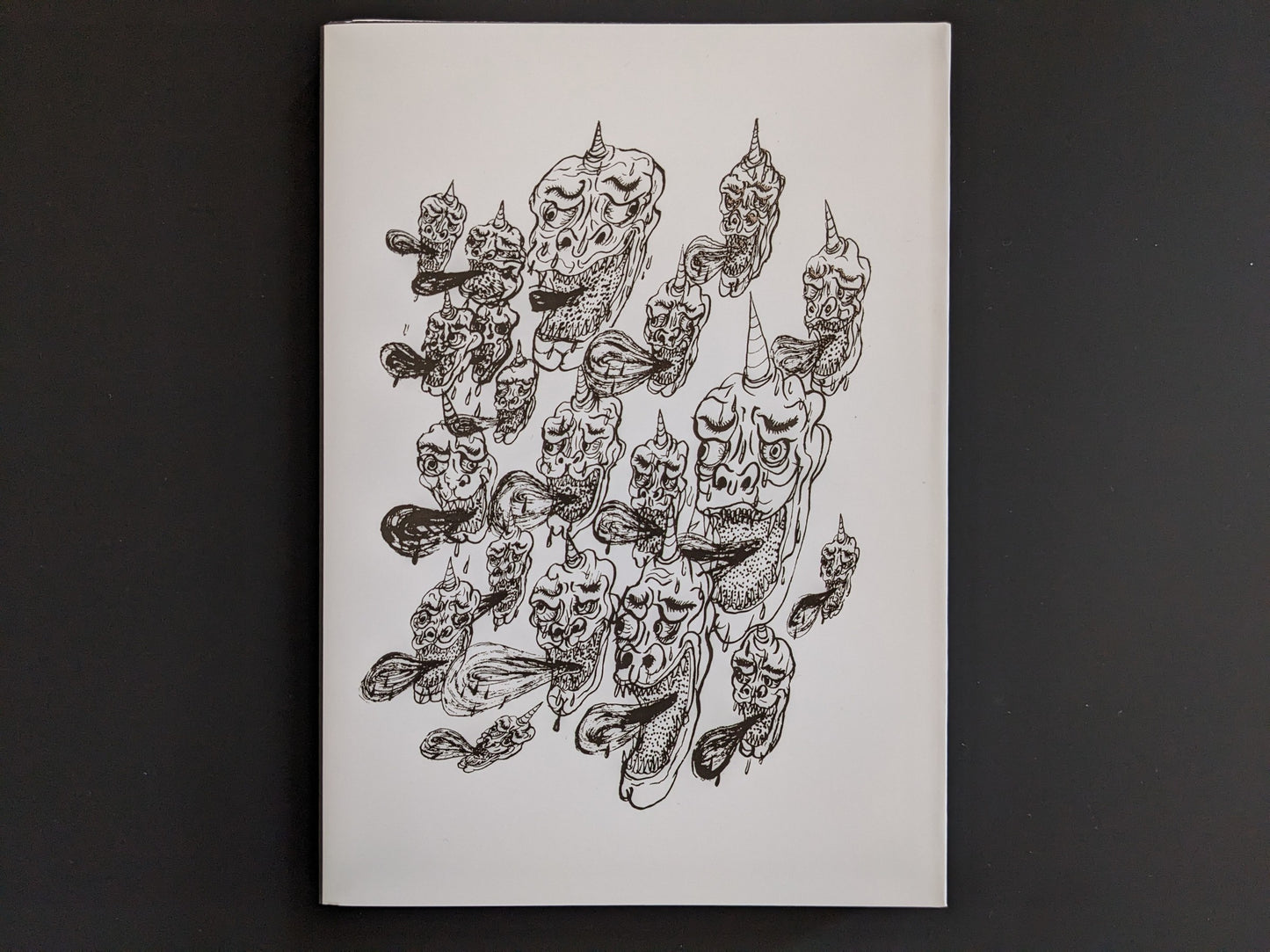 Back cover of The Life of Namazuko featuring a pattern of grotesque demon heads with horns and flowing tongues.