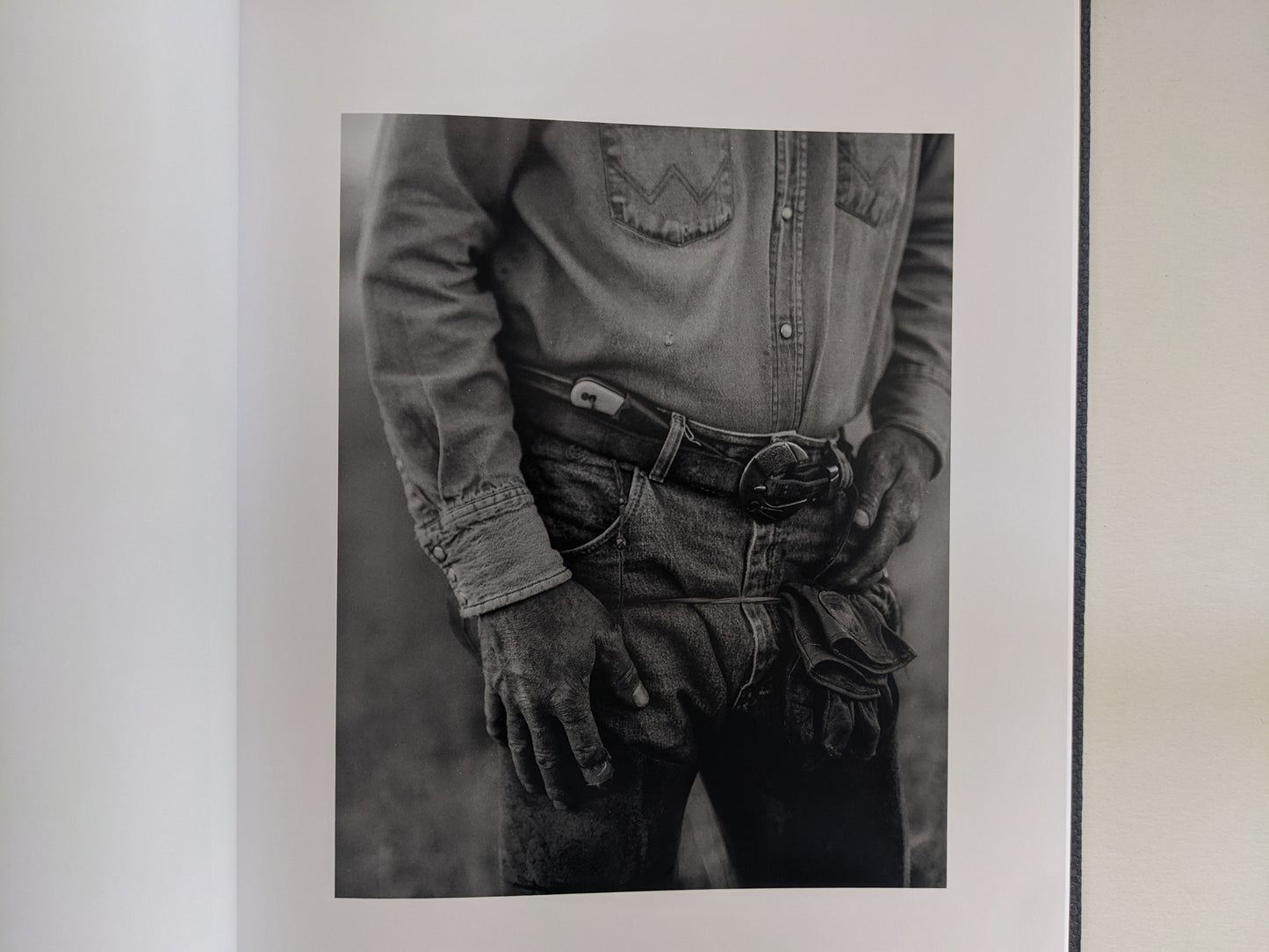 Black-and-white portrait of a rancher’s denim-clad hands and belt in 'No Fences'