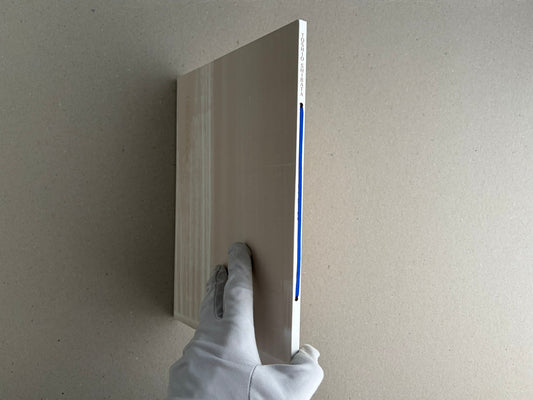 Painting – Toshio Shibata shown in side view, held upright by a gloved hand, with the blue ribbon on the spine visible.