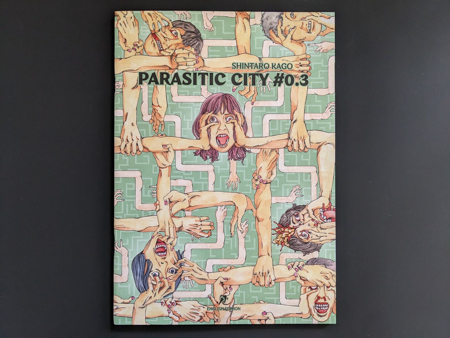 Front cover of "Parasitic City #0.3" by Shintaro Kago, showing distorted, screaming faces and entangled hands against a pastel green patterned backdrop