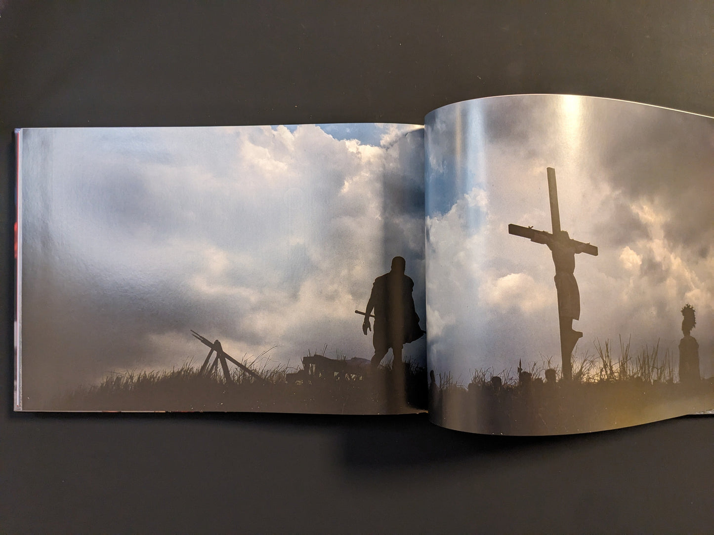 Dramatic silhouette of a man on a cross against a cloudy sky during a ritual ceremony.