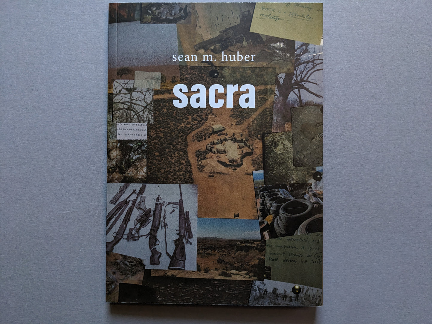 Front cover of "Sacra" by Sean M. Huber, collage of weapons, desert landscapes, and handwritten fragments