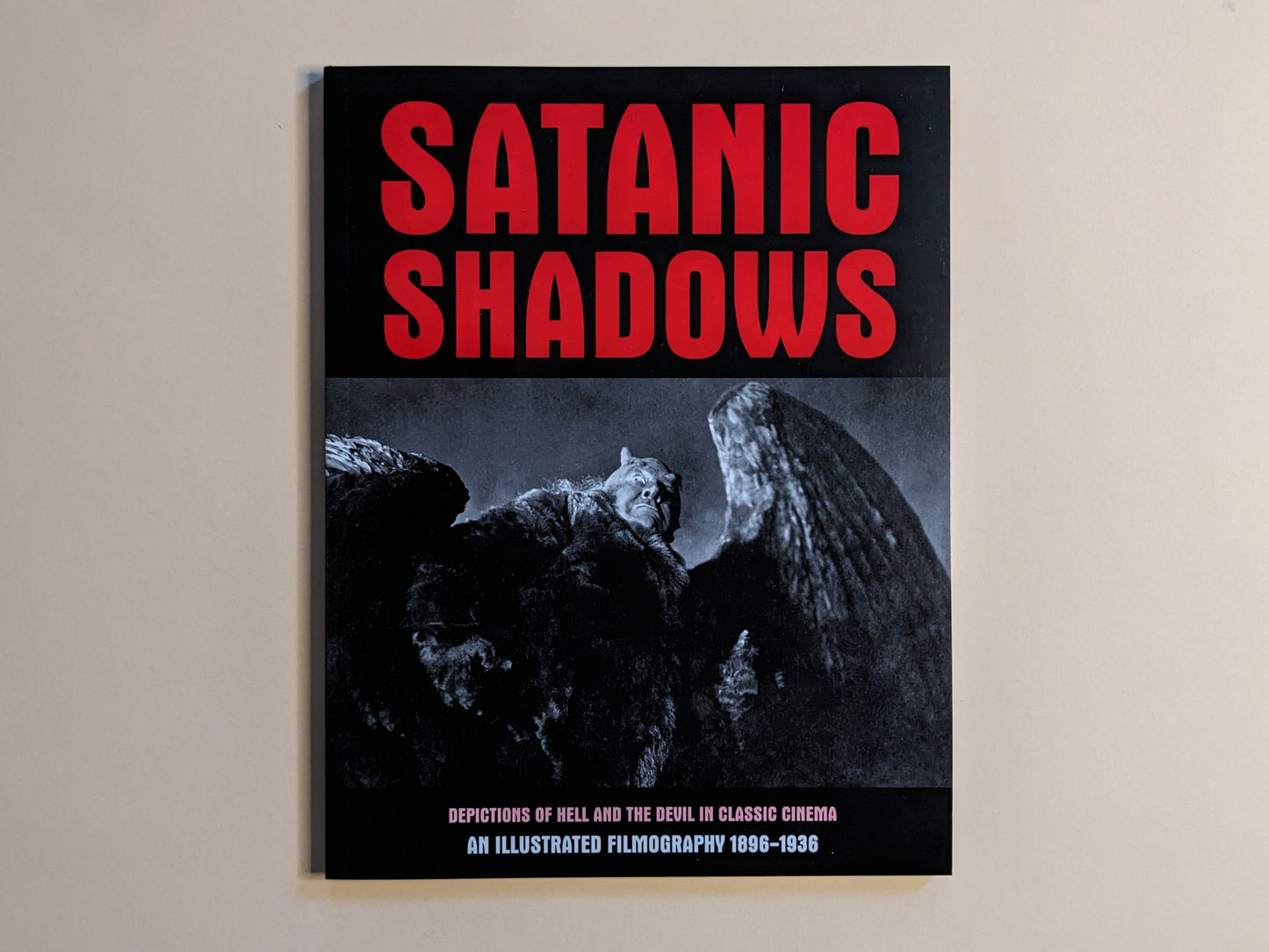 Front cover of 'Satanic Shadows', showing a red title and an image of a winged demon from early cinema.