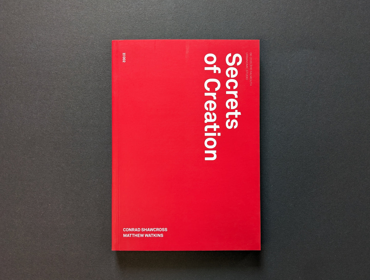 Front cover of Secrets of Creation with red minimalist layout and vertical title.