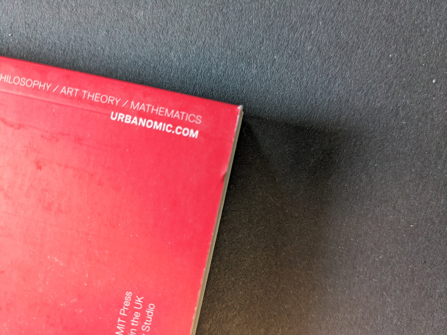 Close-up of edge wear and surface scratches on red softcover.