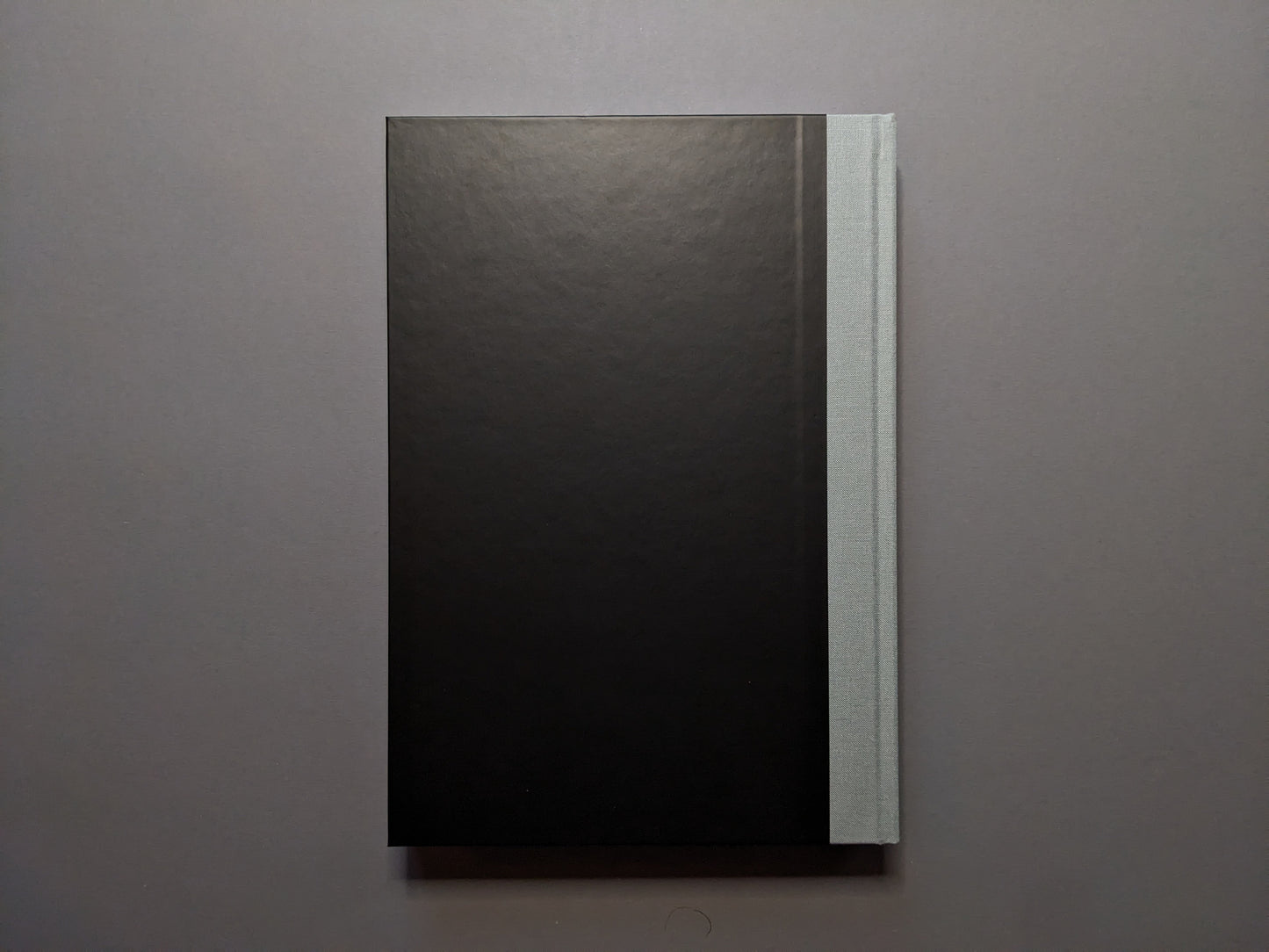Back cover of 'The Last Slogan' – minimalist black with grey cloth spine