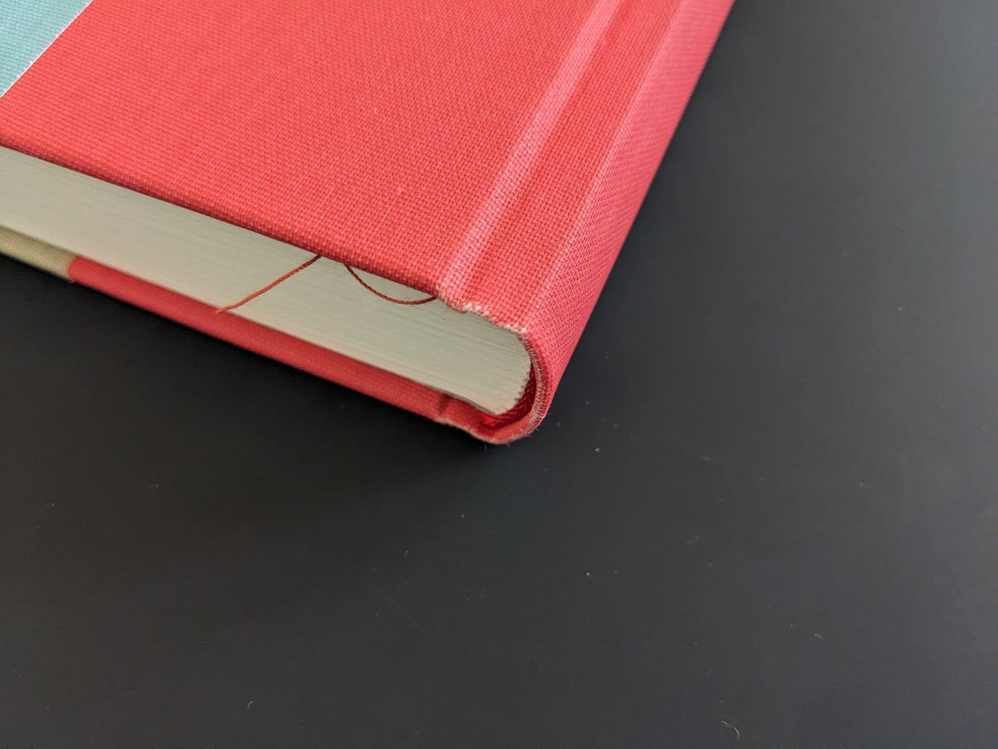 Bottom spine corner of The Pillar by Stephen Gill, red cloth cover showing frayed edges