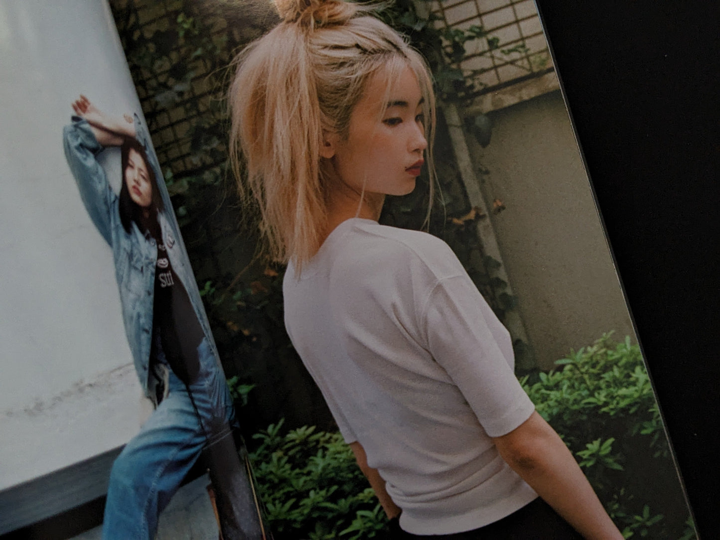 Woman with blonde hair tied up, wearing a white shirt, standing outdoors.