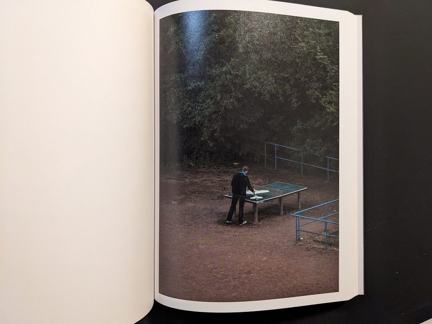 Photograph from TTP by Hayahisa Tomiyasu showing a person standing near the table under dim evening light.