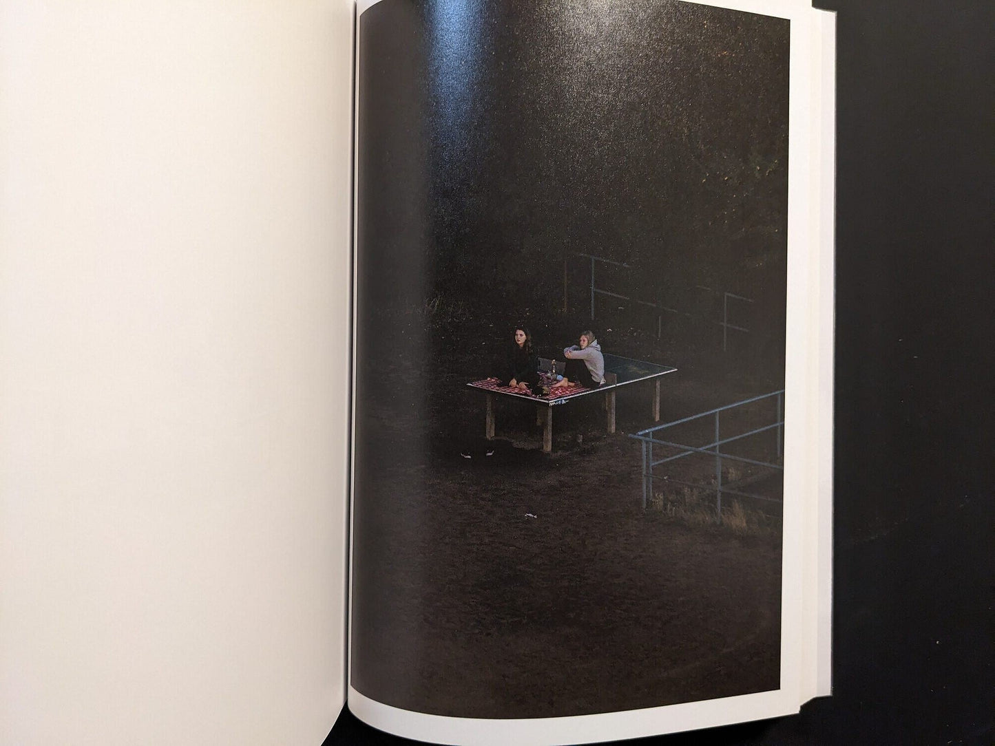 Photograph from TTP by Hayahisa Tomiyasu showing two figures lying on a table in the dark surroundings.