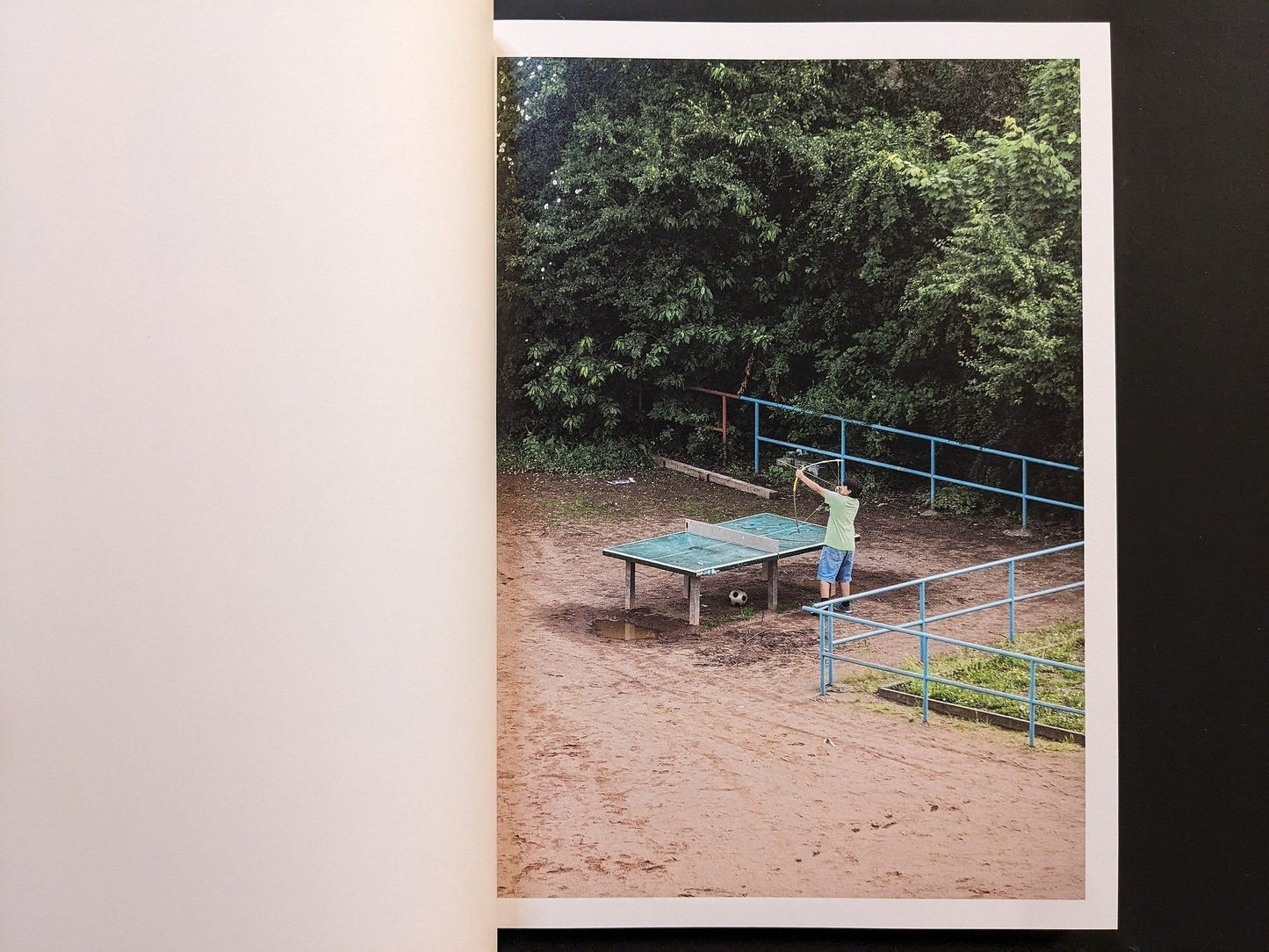 Photograph from TTP by Hayahisa Tomiyasu depicting a person standing alone beside a green ping pong table.