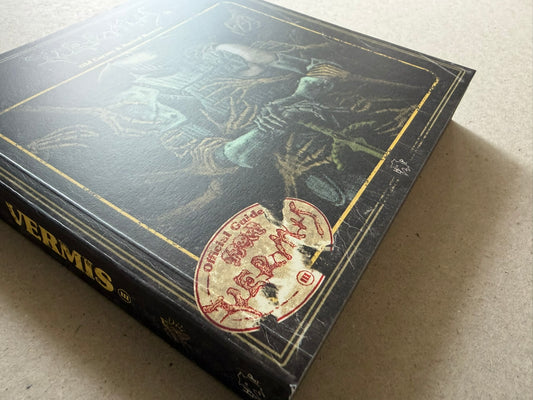 Vermis III shown at an angle, with the worn black cover, gold border, and red official-guide stamp visible.