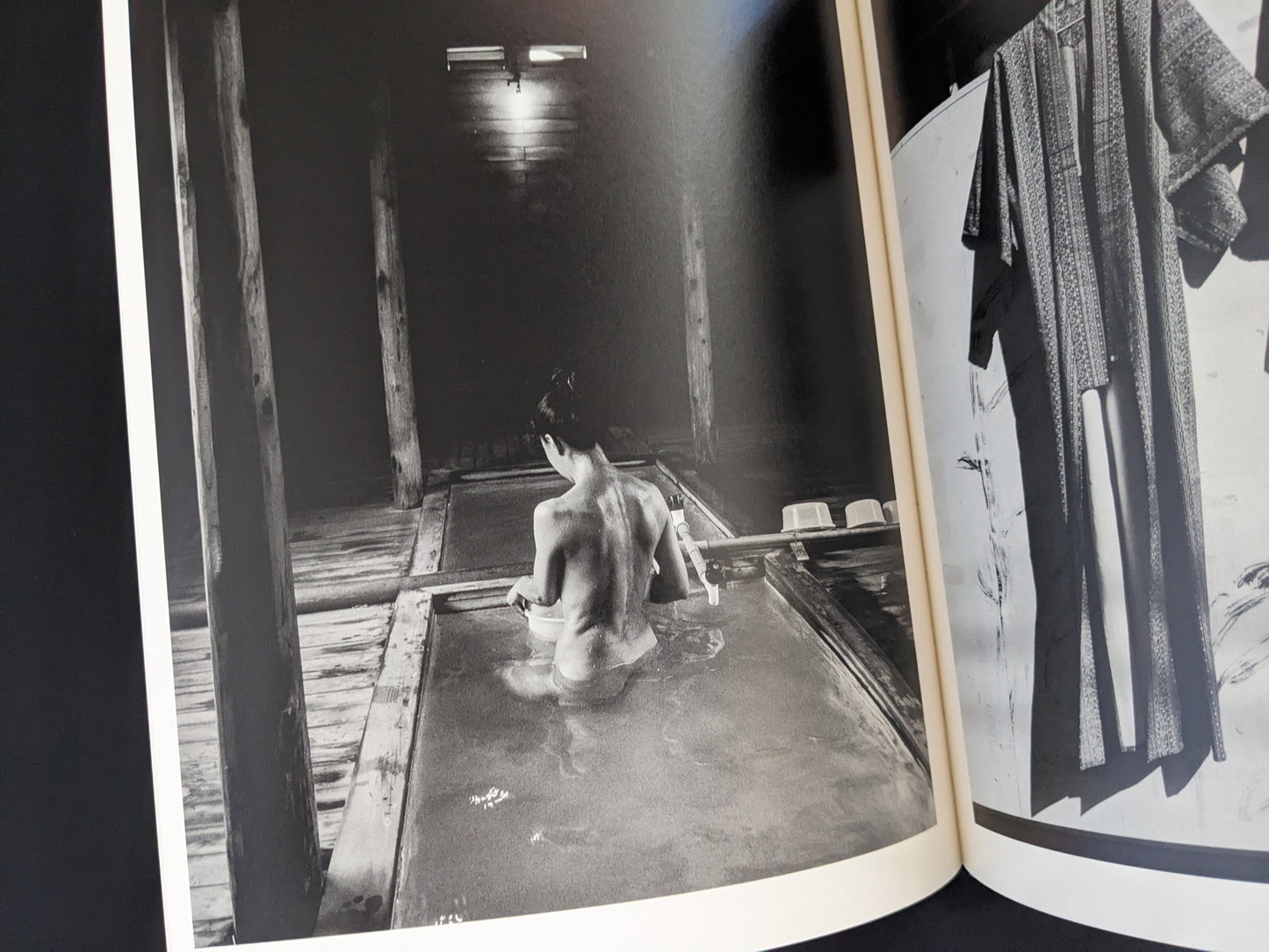 Black and white photograph of a person bathing in wooden interior from Wandering Dog