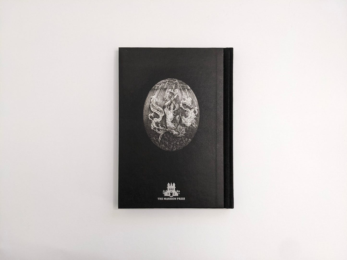 Back cover of Where Shadows Breathe: The Art of Melf, black hardcover with an oval illustration and The Mansion Press logo.