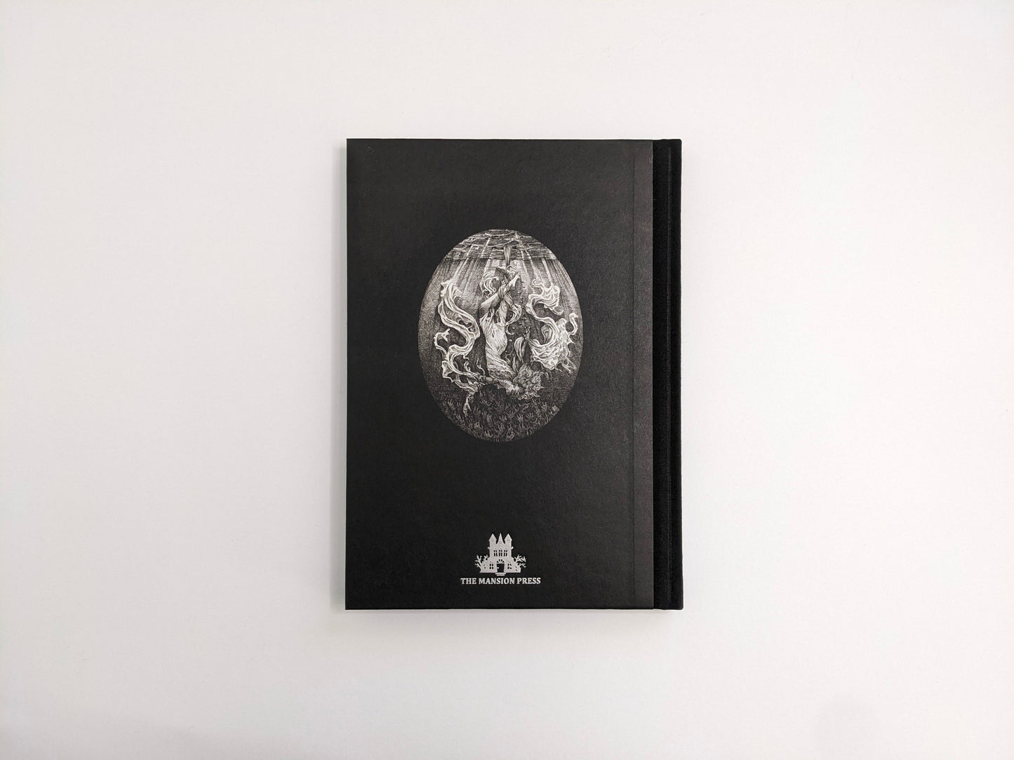 Back cover of Where Shadows Breathe: The Art of Melf, black hardcover with an oval illustration and The Mansion Press logo.