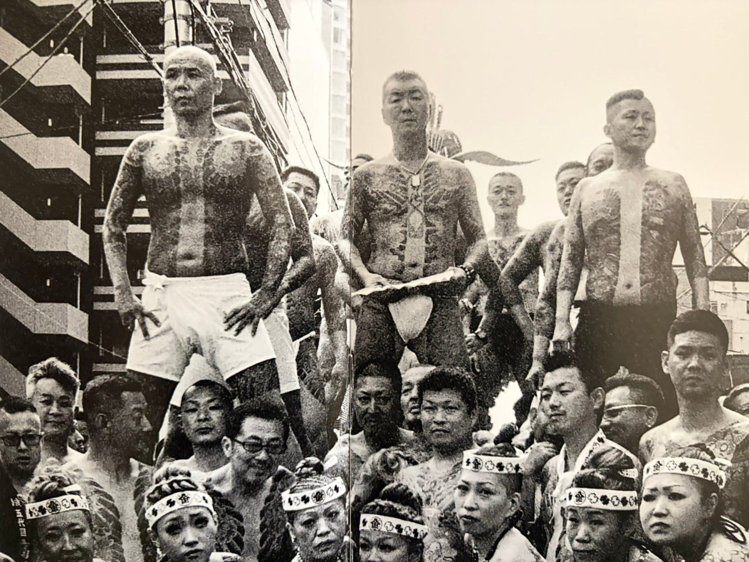 Black-and-white spread from Japanese Photobooks showing a crowd of bare-chested men in a street procession.