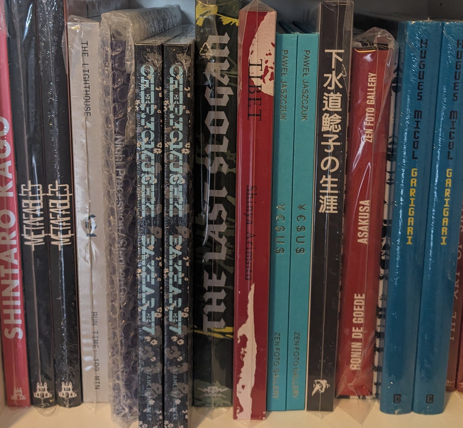 Spines of New Arrivals books arranged upright on a shelf, including photobooks and artist publications.