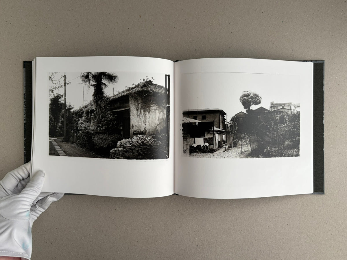 Open spread of 1980s Remnants by Daido Moriyama, showing two black-and-white photographs of rural buildings and vegetation.