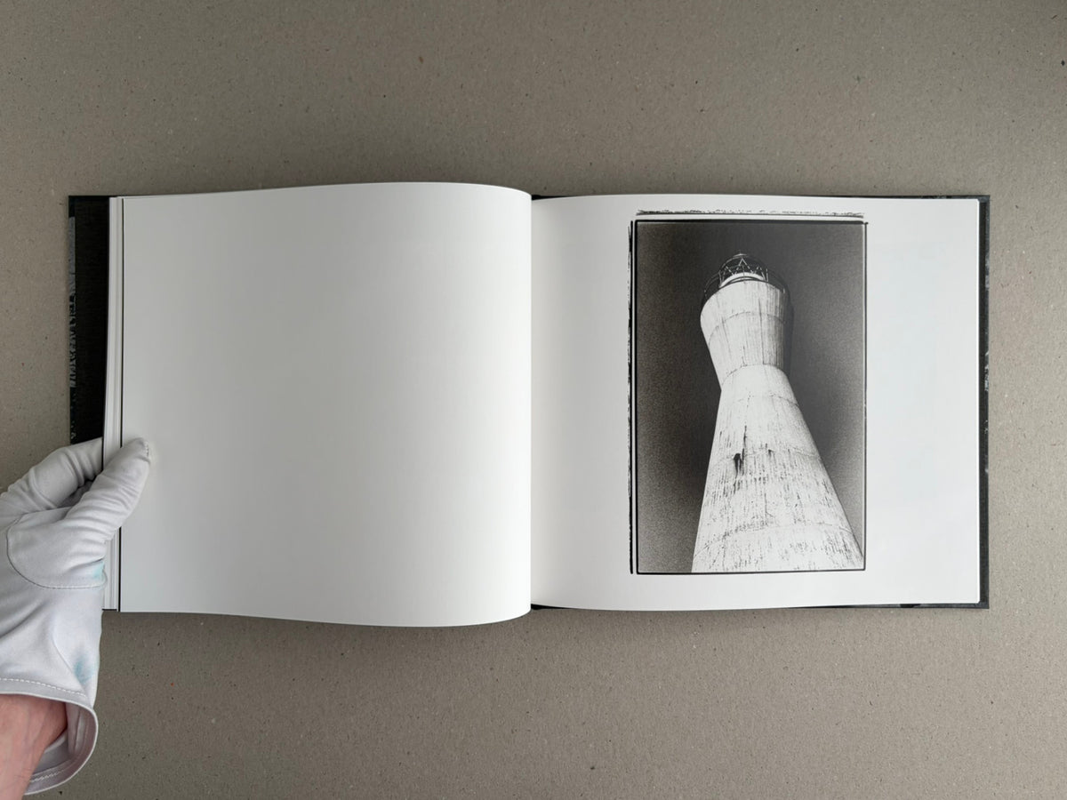 Open spread of 1980s Remnants by Daido Moriyama, with a blank left page and a black-and-white photograph of a tower on the right page.