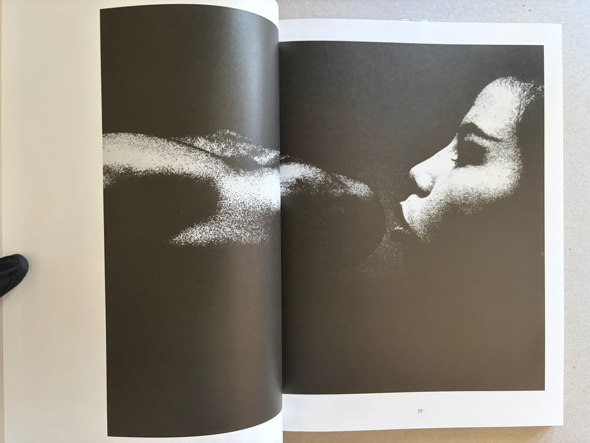 Two-page spread with a profile portrait in black and white, facing a large abstract light shape across the gutter.