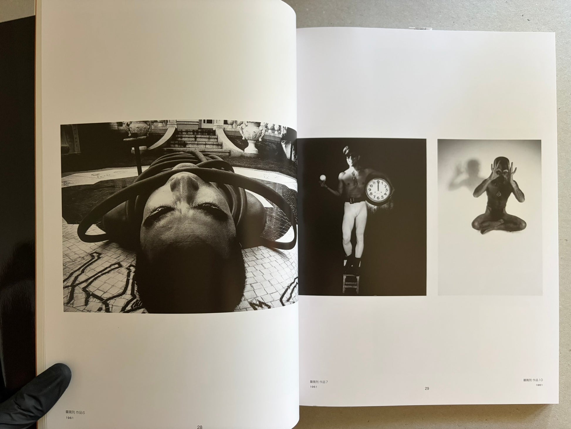 Two-page spread with three black-and-white photographs, including a reclining figure, a standing figure with a clock, and a seated figure against a pale background.