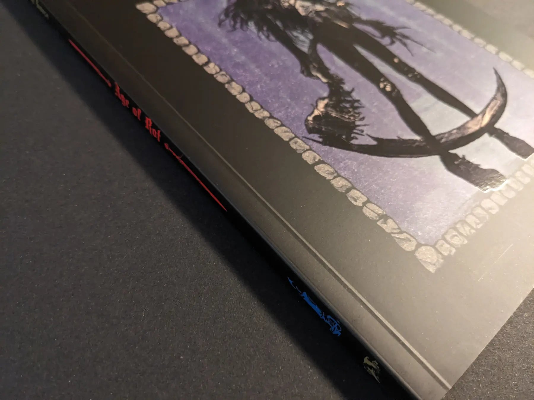 Angled view of the Age of Rot softcover reprint by Strange House, showing the illustrated front cover and printed spine.