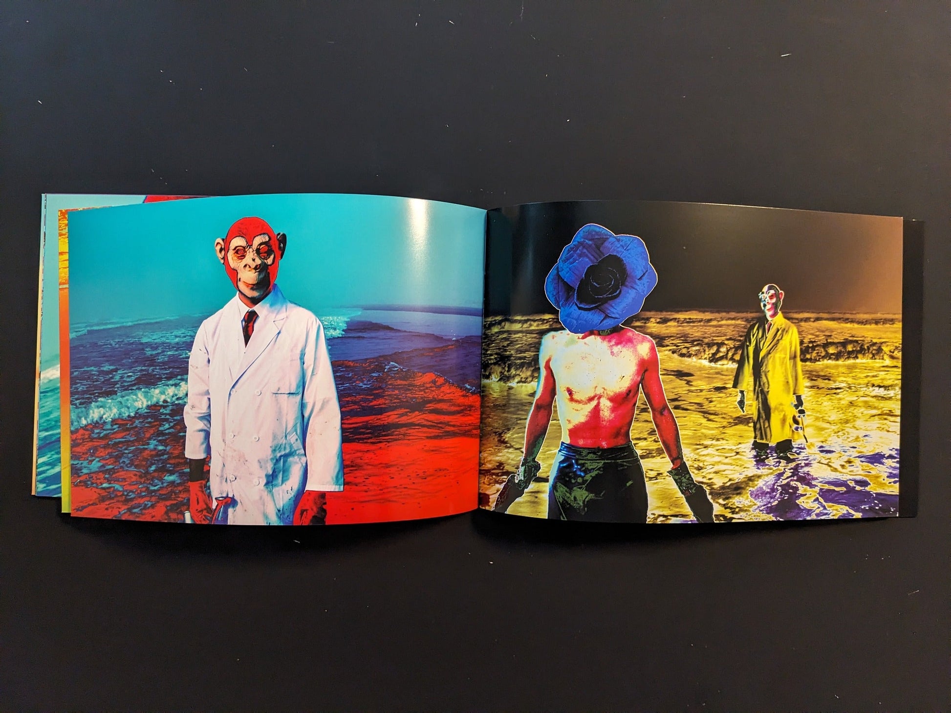 Inside spread from “AKARUIMIRAI” featuring masked or painted figures in bright coats standing on the beach in surreal, high-contrast colours.