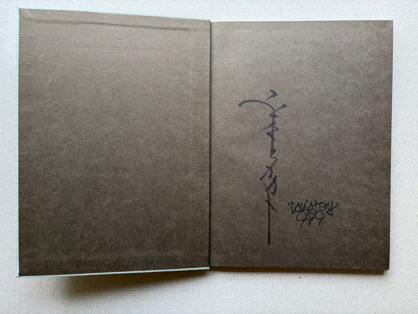 Allure of Pharmakon by Takato Yamamoto, charcoal grey endpapers with signed page spread
